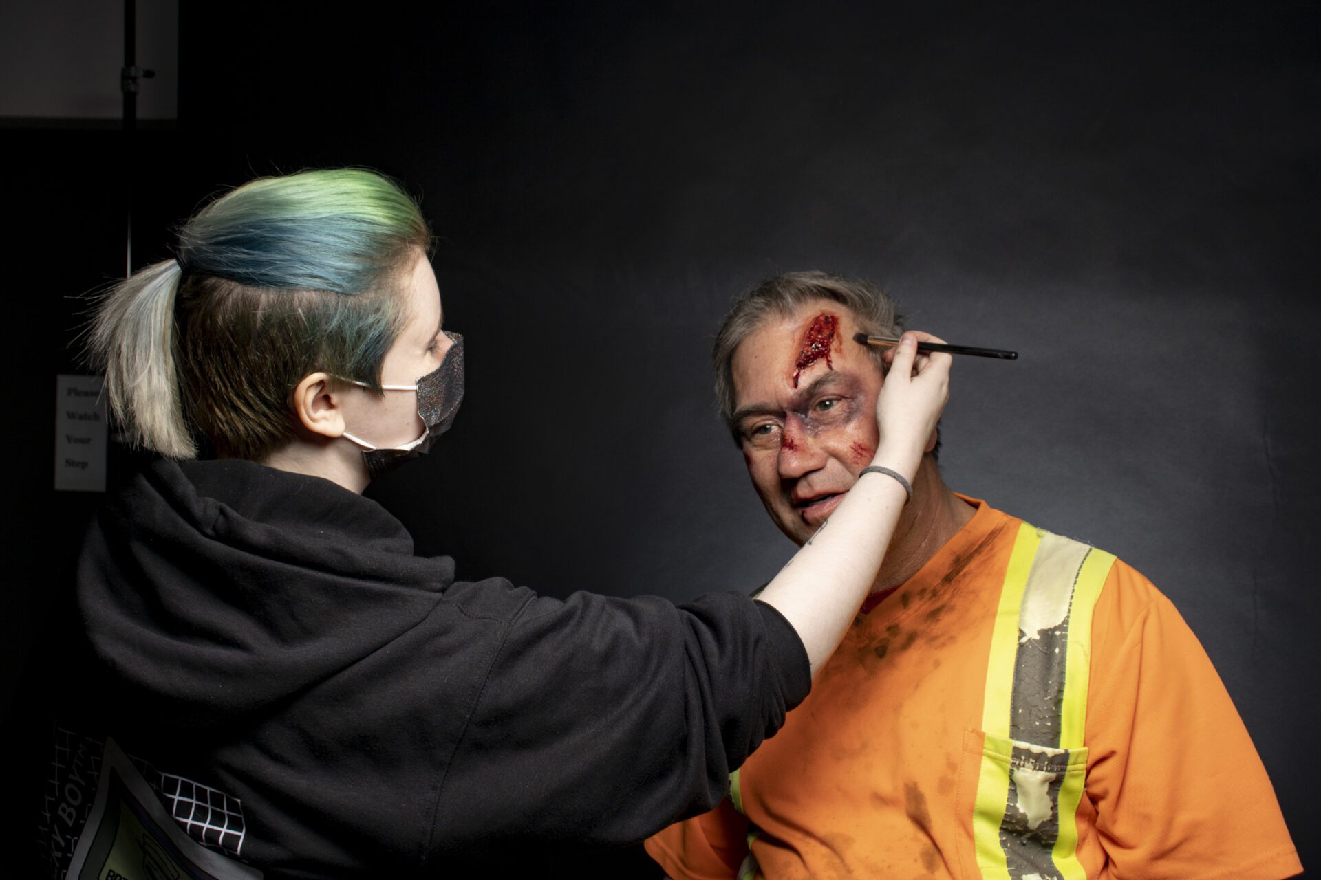 A CMU student adding makeup to a man during a class