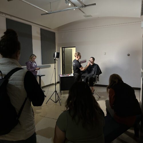 A student applying theatrical makeup